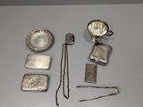 Plusieurs objets en argent sont disposés sur une surface blanche