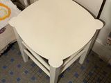 a small white table and chair in a small room