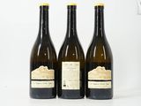 trois bouteilles de vin sont alignées sur une surface blanche