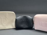 three cosmetic bags are lined up on a gray surface