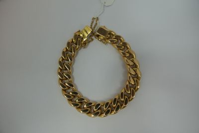 a close up of a gold chain bracelet on a white surface