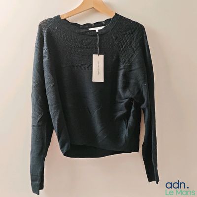 Le pull est suspendu à un cintre accroché au mur.