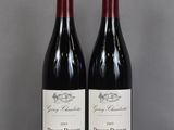 two bottles of red wine sitting on top of a glass table