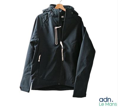 une veste noire suspendue à un cintre sur un mur blanc