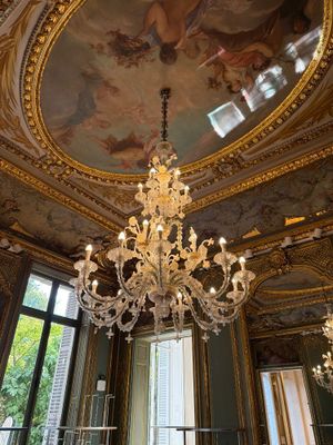 un lustre au milieu d'une pièce dont le plafond est orné d'une peinture