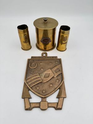 un ensemble d'objets en laiton comprenant un décapsuleur en laiton, un porte-verre en laiton et une assiette en laiton