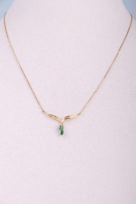 un collier en or orné d'une pierre verte autour du cou d'un mannequin