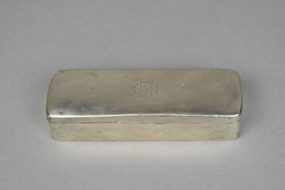 an old silver box with a silver lid sitting on a white surface