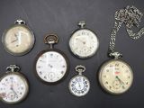 plusieurs modèles différents de montres de poche posés sur une surface noire