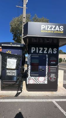 two machines that are sitting outside of a pizza shop