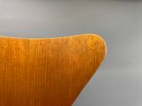 un gros plan d'une chaise en bois posée contre un mur gris