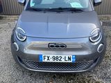une voiture grise garée devant un immeuble, à côté d'un parking