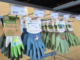 plusieurs paires de gants de jardinage suspendues à un porte-gants dans un magasin