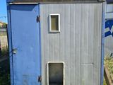 a small blue outhouse sitting in the middle of a yard