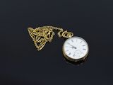 an image of a gold pocket watch with a chain on a black surface