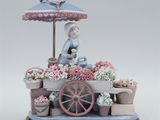 une figurine représentant une femme assise devant un étal de fleurs