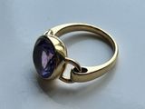 a close up of a gold ring with a purple stone