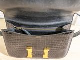 the inside of a black purse with gold handles on a wooden table