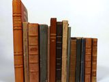several old books are stacked on top of each other on a white surface