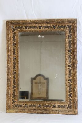 Miroir en bois stuqué sculpté patiné noir et doré.