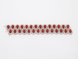a close up of a red and white bracelet on a white surface
