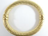 gros plan d'un bracelet en or sur une surface blanche
