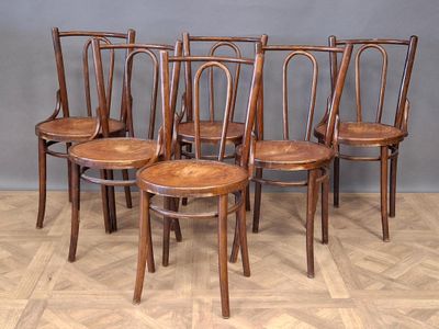 four wooden chairs are lined up in a row on a parquet floor