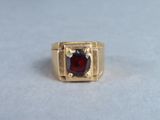 an image of a gold ring with a garnet stone