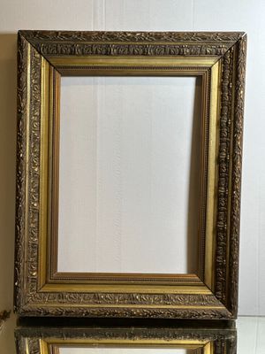 two gold frames on a white table with a wall in the background