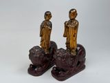 pair of asian figurines of a man and a woman on a lion