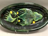 une assiette verte avec une grenouille dessus, posée sur une table
