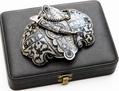 a black box with a silver brooch on top of it