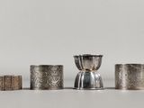 un ensemble de cinq serviettes et tasses en argent posées sur une table