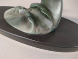 a green sculpture of a shell on a black plate
