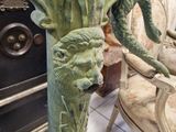 a statue of a dragon on a pedestal with a chair in the background