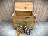 two cans of oil sitting next to a wooden box