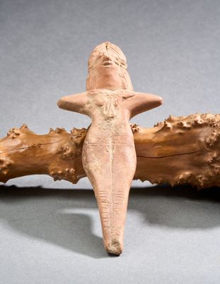 une figurine représentant une femme debout sur un morceau de bois