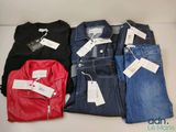 quatre paires de jeans pour homme posées sur une table, avec leurs étiquettes de prix