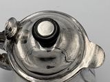 a silver teapot with a lid on a white table