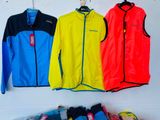 three jackets hanging on a wall next to a pile of clothes