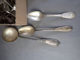 three silver spoons and two silver spoons sitting next to each other