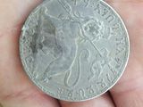 someone is holding a silver coin in their hand on a table