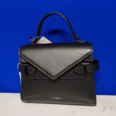 a black handbag sitting on top of a table next to a blue wall