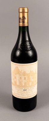 une bouteille de vin rouge sur un fond gris, avec un bâtiment en arrière-plan