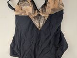 une photo d'un maillot de bain une pièce noir et beige suspendu à un cintre
