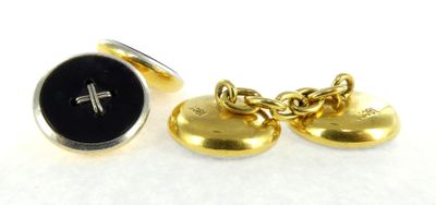 two gold tone cufflinks with a cross and a black button