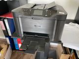une imprimante posée sur un bureau, à côté d'une pile de dossiers