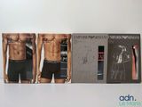 Trois boîtes de sous-vêtements pour hommes sont alignées sur une surface blanche