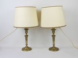 pair of brass table lamps with white lampshads on them