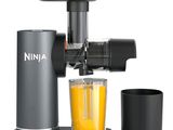 un extracteur de jus, avec un verre de jus d'orange à côté
